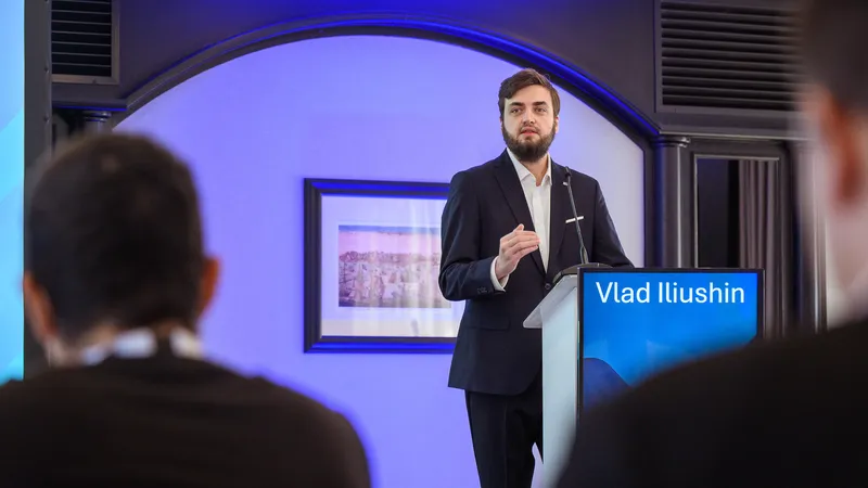 Vlad Iliushin from ELLIO in dark suit presenting at podium to seated audience at AMTSO Cyber Reserach Conference in Lisbon, Portugal in 2025.