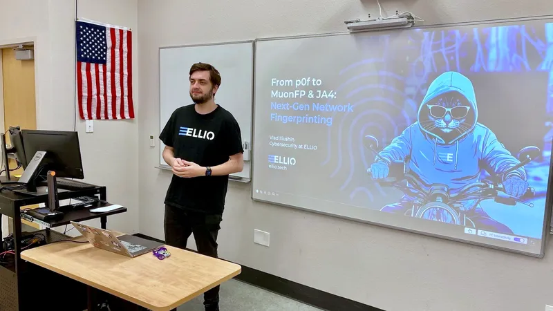 Vlad Iliushin  in ELLIO t-shirt presenting "From p0f to MuonFP & JA4: Next-Gen Network Fingerprinting" to classroom audience at BSides SWFL 2025, with cybersecurity-themed slide showing hooded hacker figure